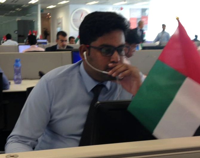 Sashank at his desk on the bank's floor in Abu Dhabi, with a UAE flag on the partition